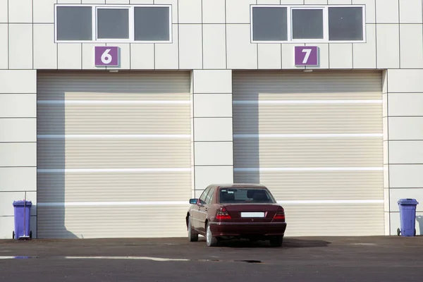 Otomatik elektrikli çekiş kapısı ya da modern binanın zemin katındaki şınav kapısı. Beyaz tekerlekli kapılı bir ticari deponun önünde. Otomatik - Yarış pisti garajı. Garajdaki kapılar