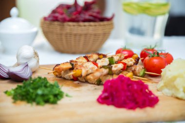 Ahşap bir şişte kuzu kebabı. Şiş kebap seti. Tahta üzerinde biftek kebabı. Kırmızı lahana turşusu. Patates püresi. Sarımsak, soğan, domates. Doğranmış kişniş. .