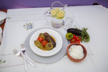 Tabağa patlıcan doldurdum. Patlıcanlar et ve pirinçle doldurulur. Patlican. Patlıcan dolgusu. Patlıcan, biber, domates. Kahverengi kasede yoğurt. Cam kavanozda doğranmış limon. .