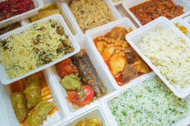 Plastik kutularda çeşitli fast food çeşitleri. Kutularda sağlıklı ve lezzetli yiyecekler var. Shah pilav. Et pirzolası. Patlıcan dolması. Doldurulmuş et