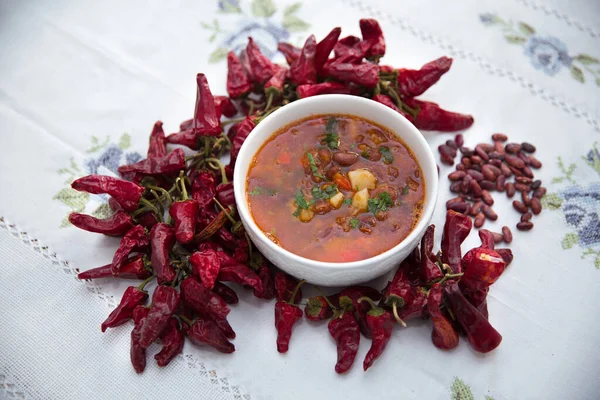 Red bean soup . Traditional Azerbaijani Red bean soup . A bowl of homemade red bean soup . Beans and red dried pepper on the table with white flowers