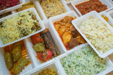 Plastik kutularda çeşitli fast food çeşitleri. Kutularda sağlıklı ve lezzetli yiyecekler var. Shah pilav. Et pirzolası. Patlıcan dolması. Doldurulmuş et