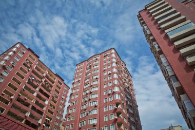BAku yakınlarındaki modern çok katlı turuncu bina cephesi. Yeni apartman. Çok katlı evler modern. Mavi gökyüzünün altındaki yüksek binalar