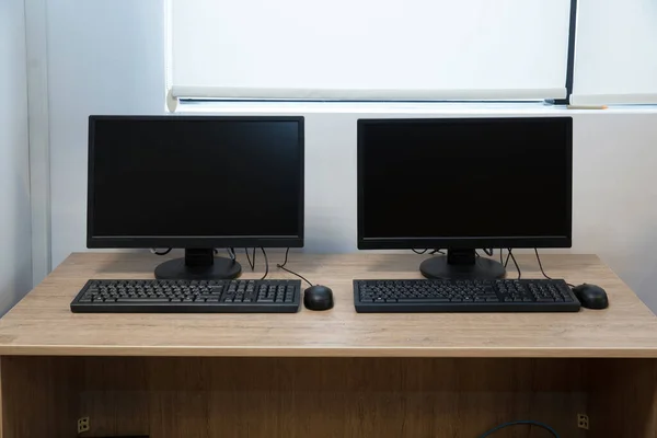Two computer monitors with a black screen on a desk . two computers and a desk . Keyboard and mouse