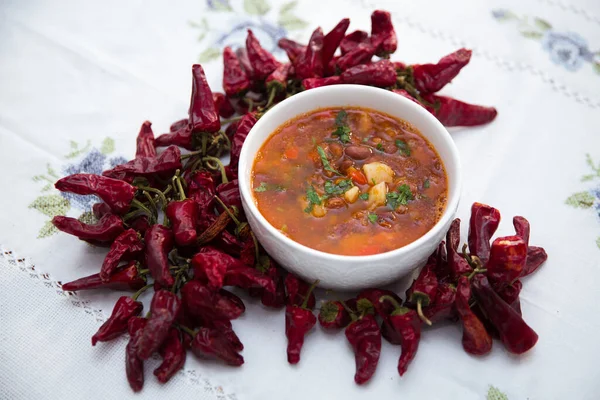 Red bean soup . Traditional Azerbaijani Red bean soup . A bowl of homemade red bean soup . Beans and red dried pepper on the table with white flowers