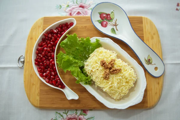 Mimosa salatası. Geleneksel Rus salatası Mimoza. Kesme tahtasından izole edilmiş. Üst Manzara. Ceviz ve mantarlı tavuk salatası. Granüle edilmiş nar. Wrendale Kaşık Dinlenme .