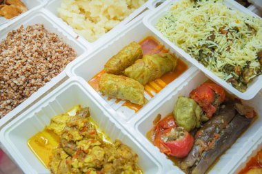 Plastik kutularda çeşitli fast food çeşitleri. Kutularda sağlıklı ve lezzetli yiyecekler var. Shah pilav. Et pirzolası. Patlıcan dolması. Doldurulmuş et
