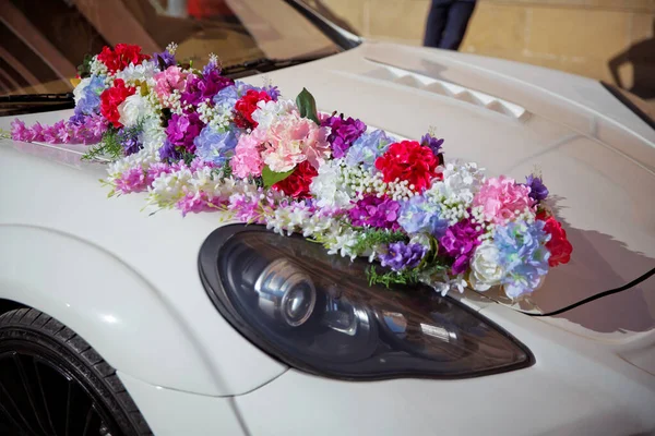 Beautiful wedding car. Front of the luxury car decorated flowers . Decorated with flowers as for a wedding . Fresh flowers on the car. Beautiful colorfull wedding bouquet on white wedding car