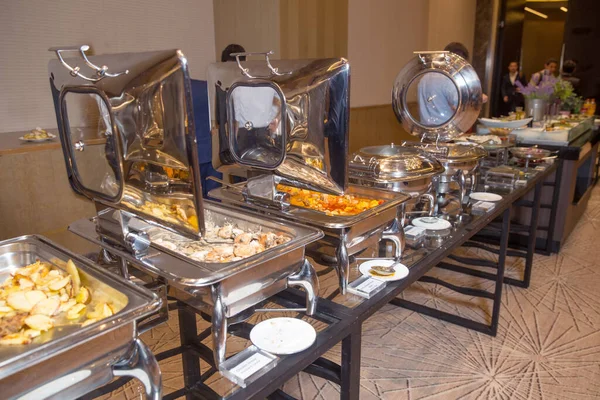 warm chafing dishes for heating food in hotel buffet banquet . Table with utensils and mirror boilers for meal . a closeup photo of dishware for a restaurant . Lamb Lamb stewed . Chicken breast .