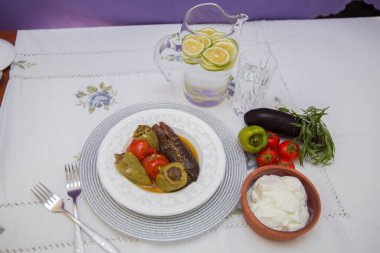 Tabağa patlıcan doldurdum. Patlıcanlar et ve pirinçle doldurulur. Patlican. Patlıcan dolgusu. Patlıcan, biber, domates. Kahverengi kasede yoğurt. Cam kavanozda doğranmış limon. .