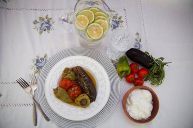 Tabağa patlıcan doldurdum. Patlıcanlar et ve pirinçle doldurulur. Patlican. Patlıcan dolgusu. Patlıcan, biber, domates. Kahverengi kasede yoğurt. Cam kavanozda doğranmış limon. .