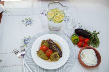 Tabağa patlıcan doldurdum. Patlıcanlar et ve pirinçle doldurulur. Patlican. Patlıcan dolgusu. Patlıcan, biber, domates. Kahverengi kasede yoğurt. Cam kavanozda doğranmış limon. .