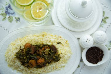 Beyaz tabakta pilav. Dilimlenmiş limon. Bir kase beyaz seramik tuz ve biber. Şah pilav. Han pilav. Beyaz seramik tencerede siyah biber. Pilavda et, yeşillik ve erik kestanesi var..
