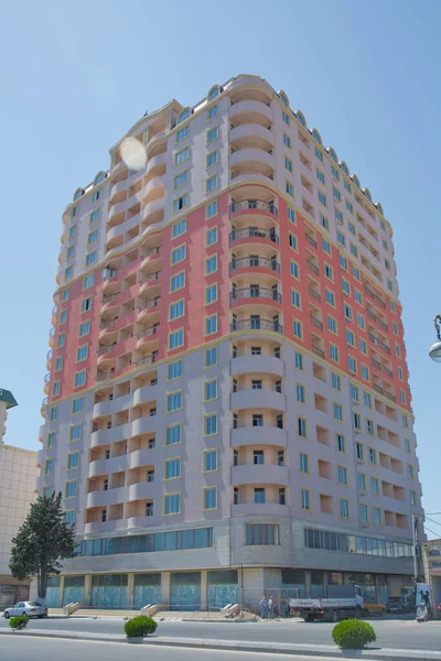 バクー近くの現代的な多階建ての新しい住宅オレンジの建物のファサード。新しいアパートだ。現代の物語の家。青空の下で高層住宅 — ストック写真
