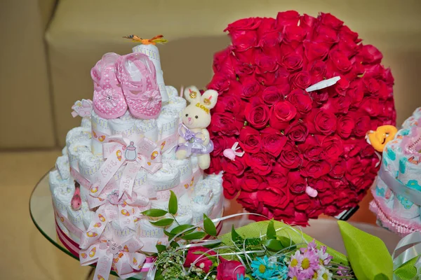 Um buquê de flores buquê de cem rosas vermelhas. Grande buquê de cem grandes rosas vermelhas flores. Sapatos infantis rosa. bolo de fralda em um presente recém-nascido .Rabbit — Fotografia de Stock