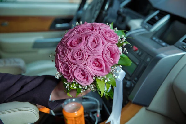 The groom was holding a bouquet of pink flowers in the car . woman holding engagement flowers, pink roses in car . Bali Catering .