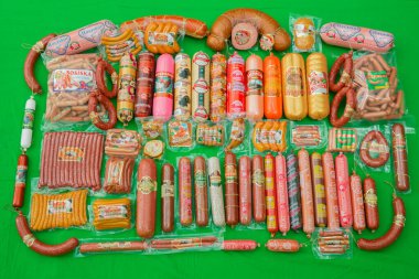 Azerbaijan baku: 27.04.2017 . Many ham sausage package isolated on green background . Group of whole tasty boiled sausages . a lot of sausages . Set with different tasty sausages clipart