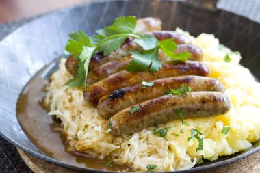 Kızarmış sosis ve lahana turşusu kızartma tavasında servis edilir.