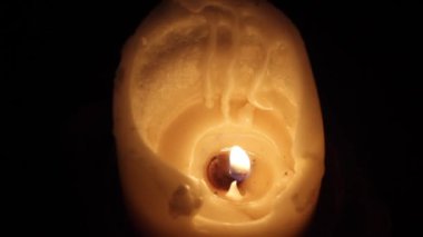 Bir beyaz mum mum ile damlama balmumu karanlık bir odada bir aleve.