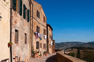 Renkli giysi ile eski taş evler. Pienza, İtalya.