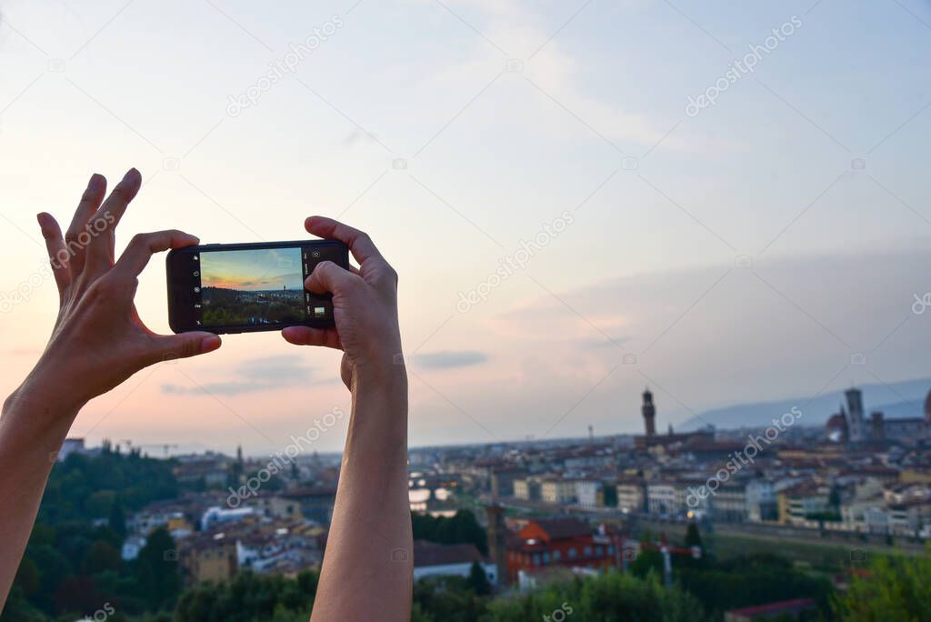 Closeup of a womaen hand with smartphone taking a panaramic picture of Florence, Italy