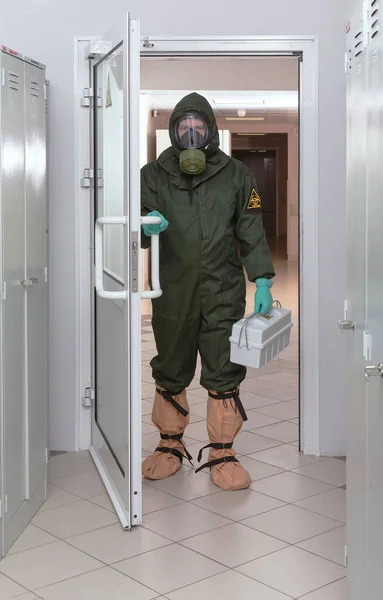 Biyolojik tehlike giysisi içinde kutu taşıyan adamlar.