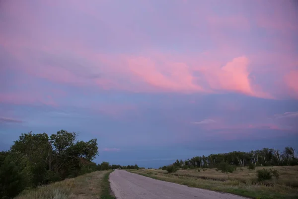 Pôr do sol no céu nublado sobre a estrada — Fotografia de Stock