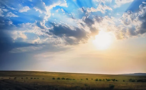 Sonnenuntergang im bewölkten Himmel über dem Feld — Stockfoto