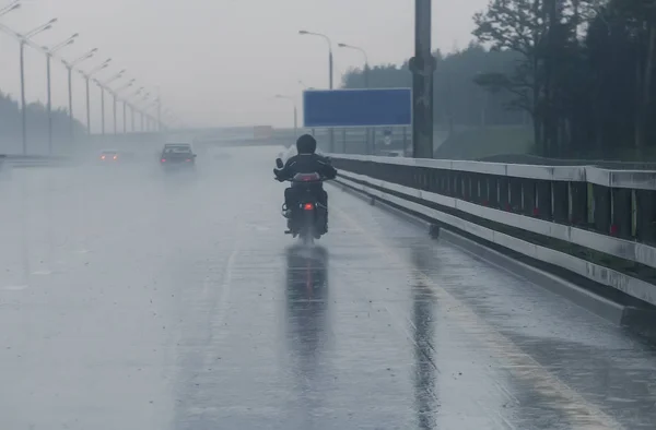 Motociclista se mueve en motocicleta a tiempo lluvioso —  Fotos de Stock