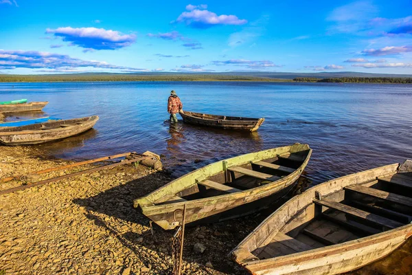 Pescador andando na água com um barco — Fotografia de Stock