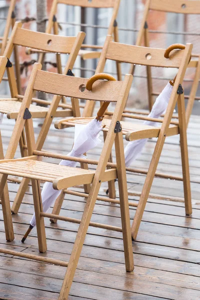 Wooden chairs and umbrellas in the rain — Stock Photo, Image