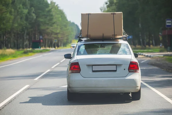 Auto mit Pappschachtel am oberen Kofferraum bewegt sich entlang der Straße — Stockfoto