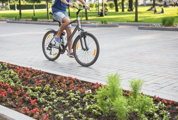 Ciclista está en bicicleta a lo largo del césped con flores — Foto de Stock
