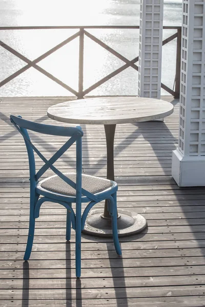 Caffè all'aperto con tavolo e sedia in legno in riva al mare nel morni — Foto Stock