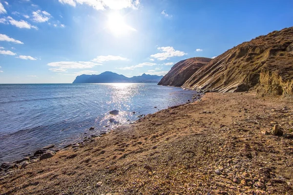 Kayalık plaj güneşli gökyüzü ve dağlar
