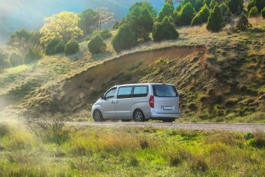 Minivan yazın bir dağ yolunda ilerliyor. 