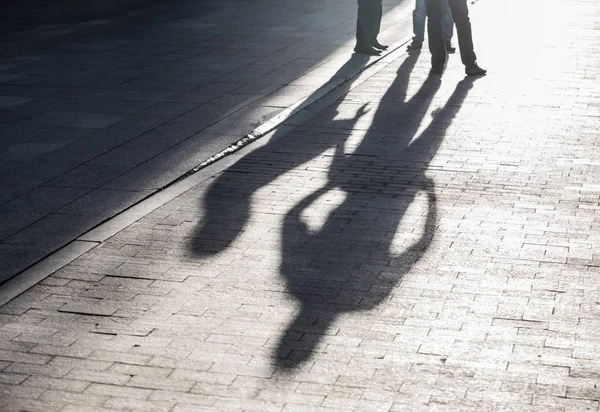 Ombre da tre uomini in piedi in piazza — Foto Stock