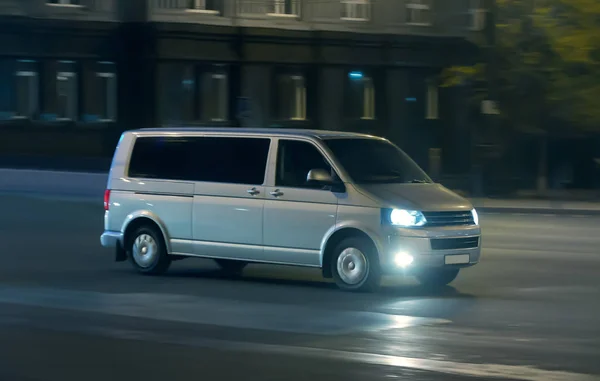 Minivan moves at night on a city street — Stockfoto