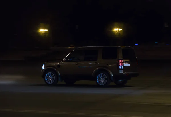 SUV rides at night on a street — Stok fotoğraf