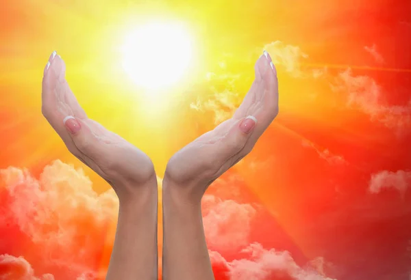 Female hands around the sun in a cloudy sky — Stock Photo, Image