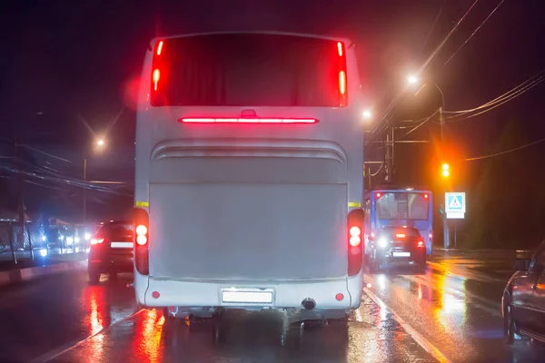 Autobus se pohybuje v noci v dešti na město — Stock fotografie