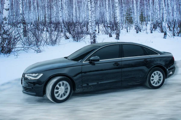 Černé auto se pohybuje v zimě na zasněžené silnici — Stock fotografie
