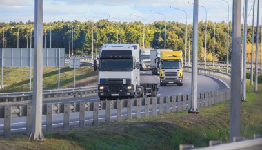 Taşrada bir kavşak boyunca giden kamyonlar