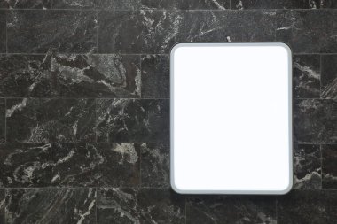 Light information rectangular panel on the wall of dark marble tiles