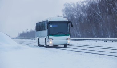 Otobüs alacakaranlıkta Karlı bir yolda ilerliyor.
