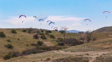 Paraşütçüler dağların üzerinden uçar.