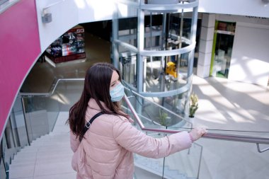 Boş alışveriş merkezinde maskeli yalnız bir kız.