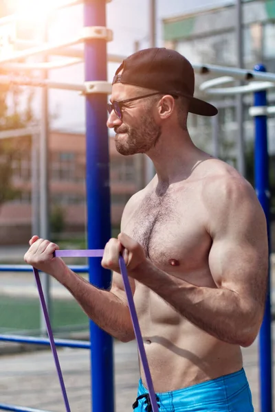 Güçlü genç adam dışarıda lastik egzersizler yapıyor.