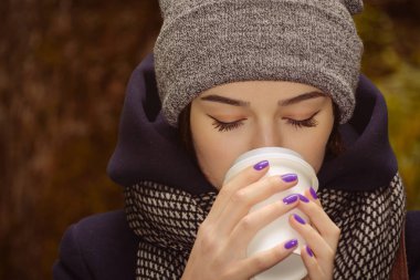 Genç bayan sıcak kahve içiyor.