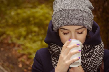 Genç bayan sıcak kahve içiyor.